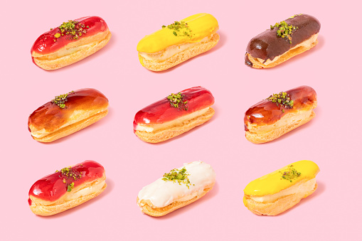Pattern of assortment of eclairs with different topping on pink background. Differentiation and variability concept