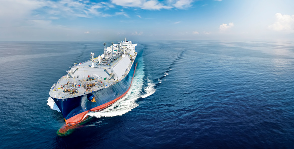 Vista frontal de un gran buque cisterna de GNL que viaja a toda velocidad sobre el tranquilo océano azul photo