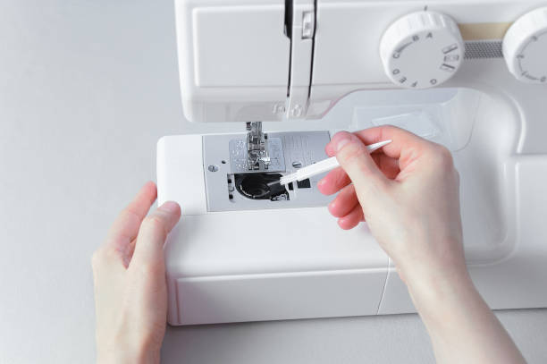 Cleaning the sewing machine with  brush. Cleaning the sewing machine with a brush. Dust removal. sewing machine stock pictures, royalty-free photos & images