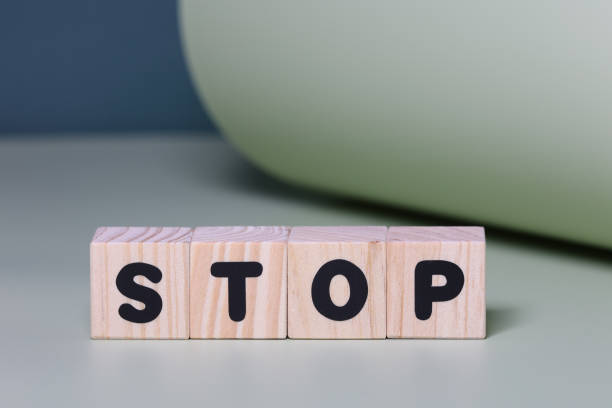 istock STOP word on wooden block  on green background 1421015556