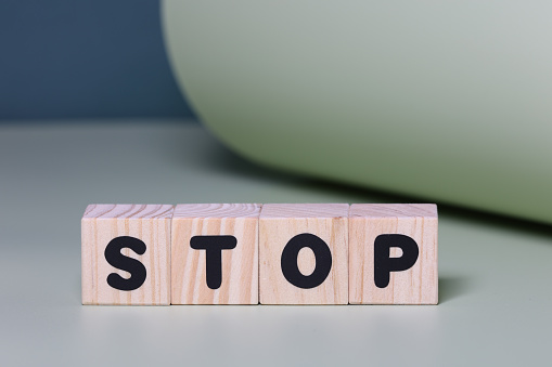 STOP word on wooden block  on green background