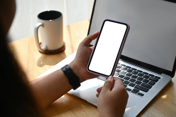 istock Over shoulder and Close up with Asian female using smartphone and laptop, blank screen of devices, Domestic life concept. 1421016101