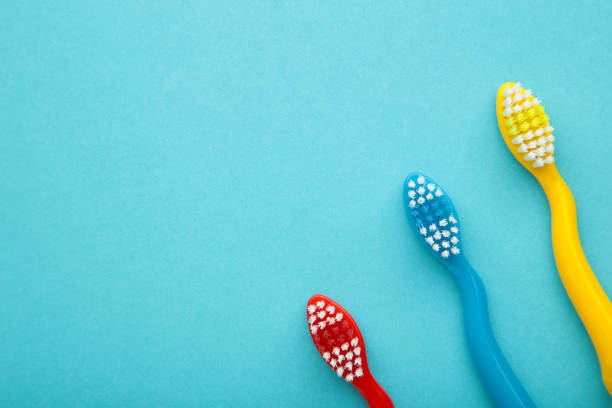 istock Colorful toothbrushes on blue background with copy space 1421018196