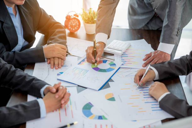 istock Group professional business people person working together to analyze in office, work together to discuss company financial statistics report, brainstorm ideas, and graph datum documents on the table. 1421018536