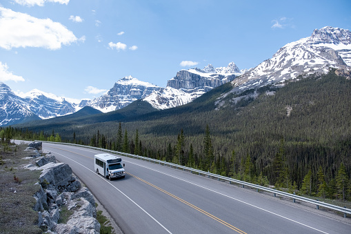 An RV travels along a scenic highway through the Canadian Rockies