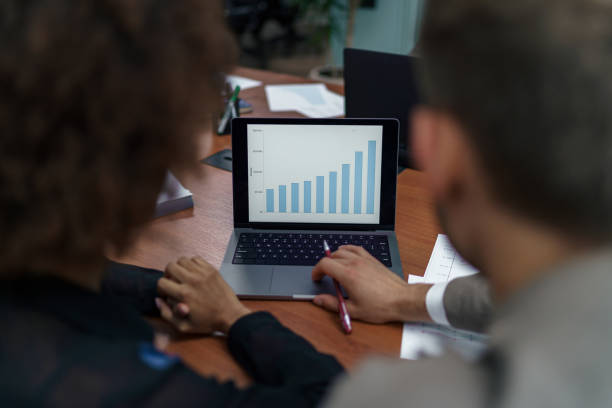istock Two businesspartners working together in modern coworking and looking laptop. Back view 1421022364