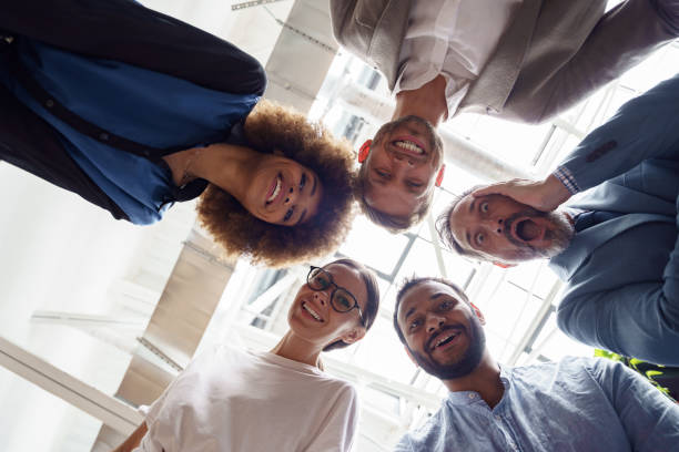 istock Below view of several happy business partners looking at camera while embracing each other 1421023138