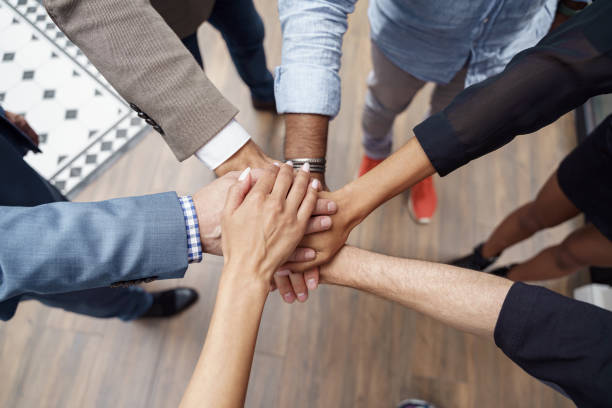 Top view of group multi ethnic coworkers stacked hands together as concept of corporate unity stock photo