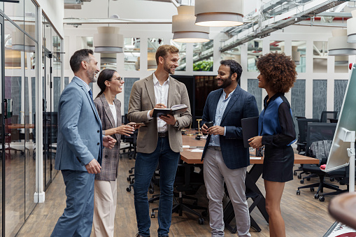 Businesspeople talking while standing in office during break. Teamwork concept. High quality photo