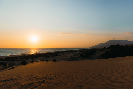 Dramatic landscape with sand dunes, Mediterranean sea and the mountain peaks during bright spring sunset in Patara, Antalya province