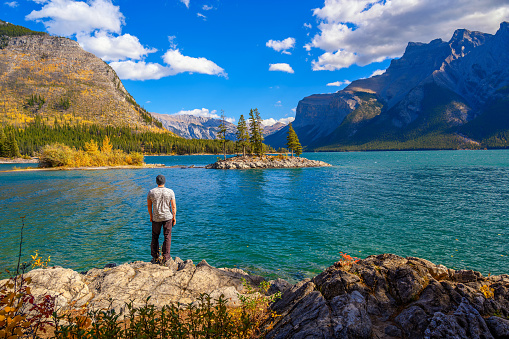 Young hiker standing at Lake Minnewanka in Banff National Park, Canada. Minnewanka is a glacial lake and the 2nd longest lake in the mountain parks of the Canadian Rockies.