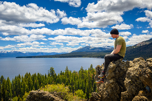 Hiker enjoying the view of Lake Tahoe from the Eagle Rock in California, with Sierra Nevada Mountains in the background.