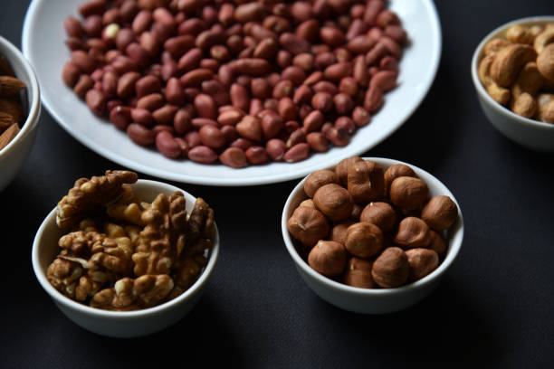 istock Peanuts on a white plate on a black background. Delicious walnut breakfast with walnuts, cashews and almonds. 1421028503