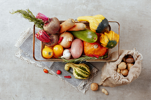 autumn flat lay on a concrete background with pumpkins, beetroot, basket, autumn leaf, autumn vegetables and nuts.