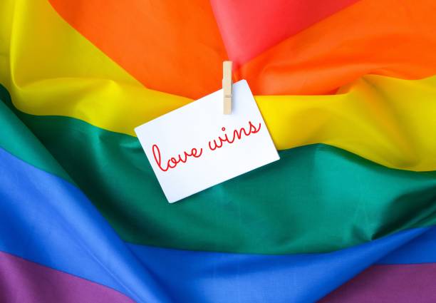 istock Rainbow flag with text LOVE WINS message on paper note. Rainbow lgbtq flag made from silk material. Symbol of LGBTQ pride month. Equal rights. 1421034590