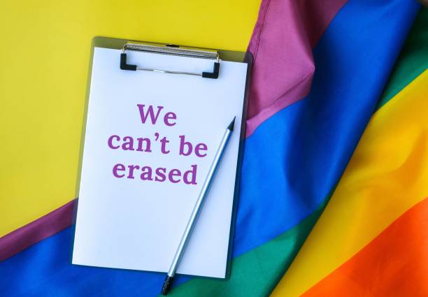 istock Rainbow flag with text WE CANT BE ERASED message paper note. Rainbow lgbtq flag made from silk material. Symbol of LGBTQ pride month. Equal rights 1421034612