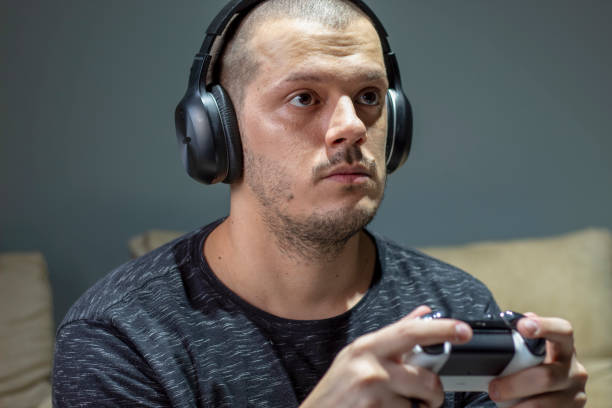 istock Man playing video games with headphone - side view 1421034845