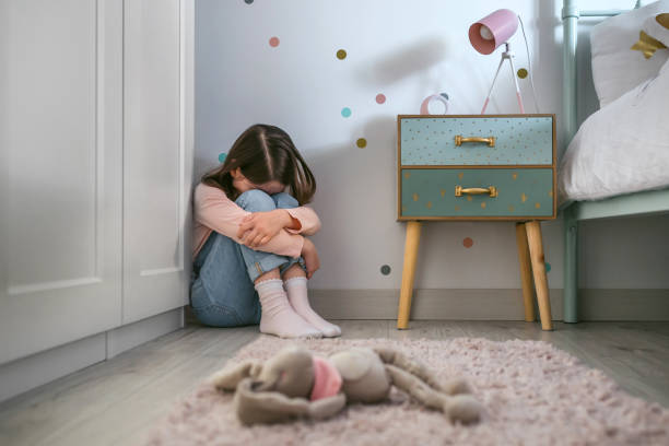 triste petite fille assise sur le sol de sa chambre avec un jouet en peluche couché - unrecognizable person one person child childhood photos et images de collection