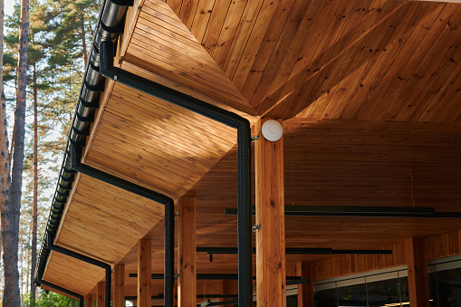 The roof of an open veranda made of wood trim with plastic pipes for rain gutters, an element of architecture
