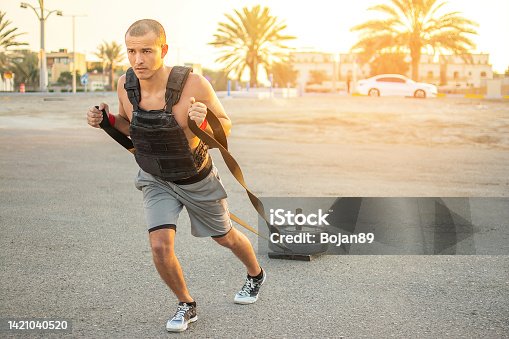 istock Handsome sporty man wearing a heavy jacket pulling weight sled outdoors. 1421040520