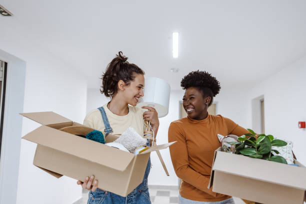 istock Cheerful friends carrying cardboard boxes with belongings 1421047577