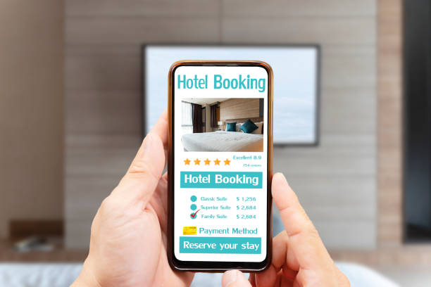 istock Man hand holding smartphone with hotel booking screen in home app 1421048747