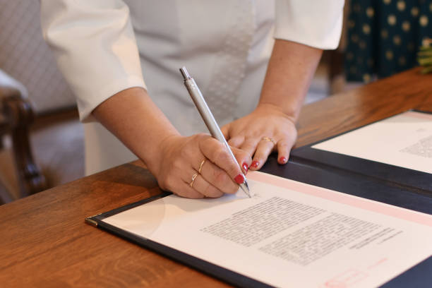 The bride signs the marriage registration documents A bride signs the marriage registration documents fiancé stock pictures, royalty-free photos & images