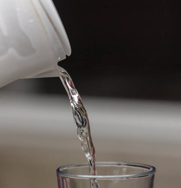 Water poured from jug into glass on a blue background
