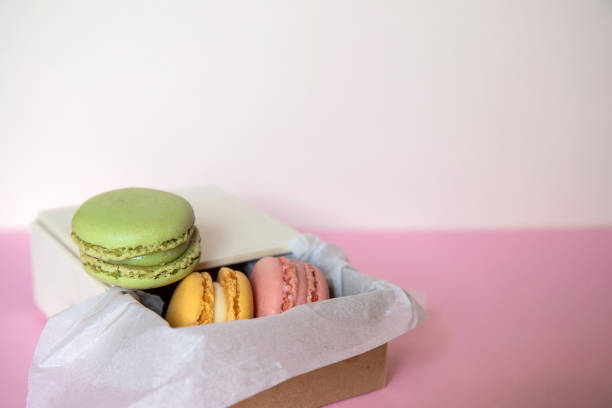 istock Cardboard box with three macarons inside, green, pink and blue, on a pink background. Concept of sweet temptation, caprice, gift. 1421053042