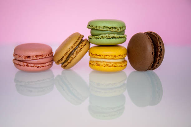 istock Pile of macarons, of different colors, on a pink background, with reflection. 1421053048