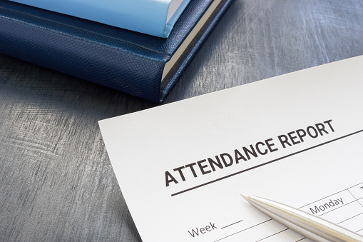 Attendance report form and a pen near notepad.