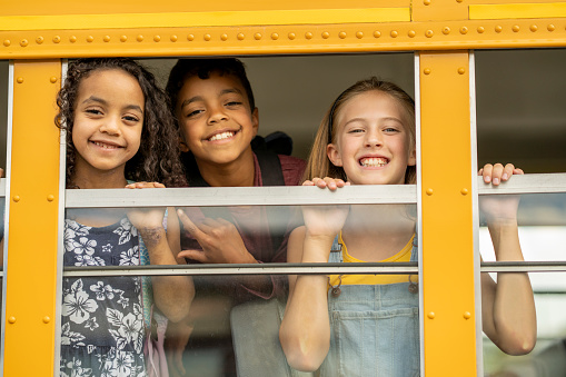 Group of multi-ethnic elementary school children (10-12 years) getting on school bus.  Shallow depth of field.