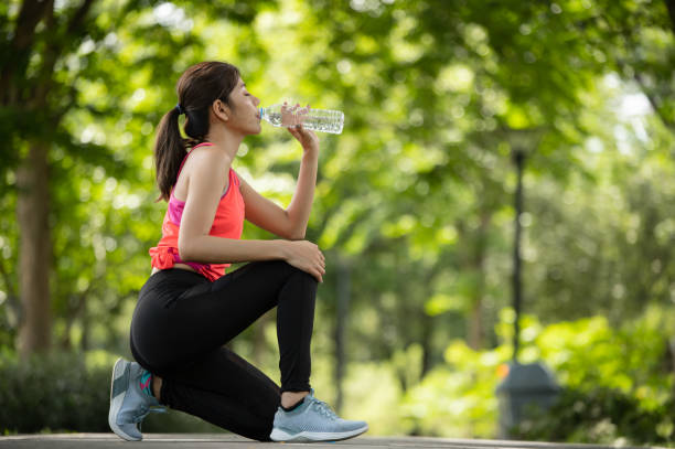 istock Attractive young runner woman drinking water on road when she finished running training 1421055749