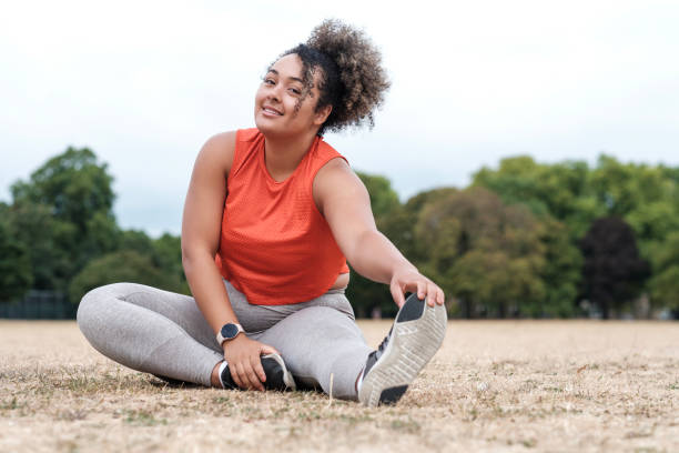 istock A young chubby woman is stretching on the grass in a park. 1421055862