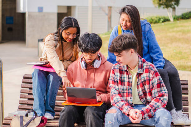 istock Image of young concentrated students sitting in bench. Looking aside while using laptop computer.ed 1421058145