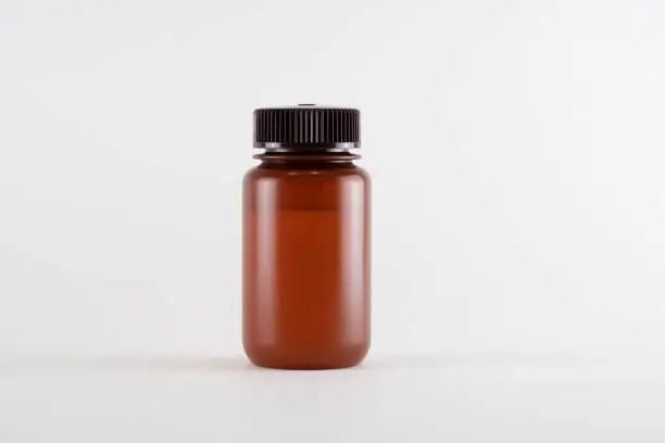 Photo of Brown amber medicine glass bottle of essential oil isolated on white background