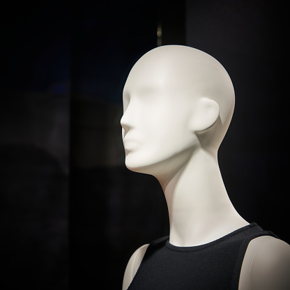 A closeup shot of a mannequin's head in a clothing shop with a blur background