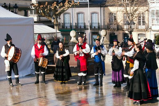 Vilalba, Lugo, Spain- December 21, 2021: Folk musicians wearing traditional clothing, playing bagpipes and drums in the street , Vilalba, Lugo province, Galicia, Spain.