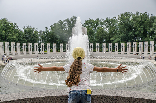 Teenage girl embracing Fountain at World War II memorial in Washington DC during summer day