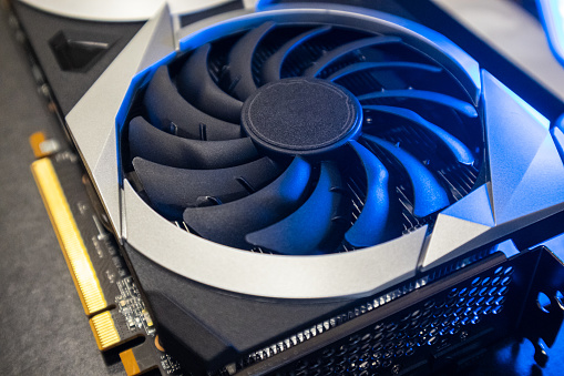 Gpu graphics card top view. Cooler fan close-up in bright blue light, PC hardware details. Components from computer cooling system with selective focus