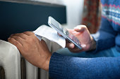 Man trying to warm up near a heater