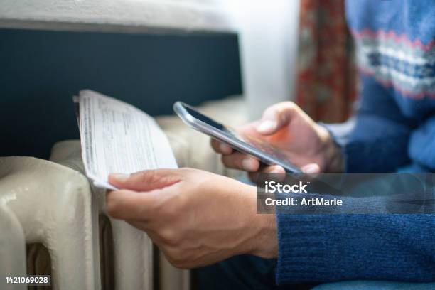 Man Trying To Warm Up Near A Heater Stock Photo - Download Image Now - Financial Bill, Gas, Heat - Temperature