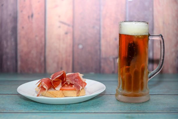 Ice cold mug of beer with a Jamon appetizer, on a wooden table