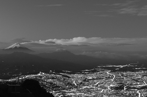 The city still has the lights on just as the sun rises, in the foreground Quito back left the fabulous Cotopaxi volcano