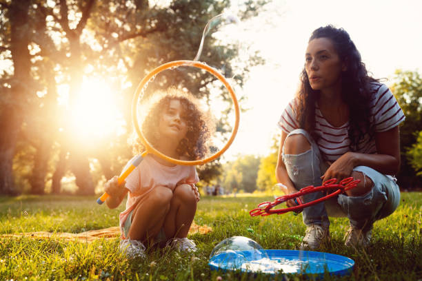 istock Mother and daughter, playing in the nature, while making soap bubbles with bubble wand 1421071277