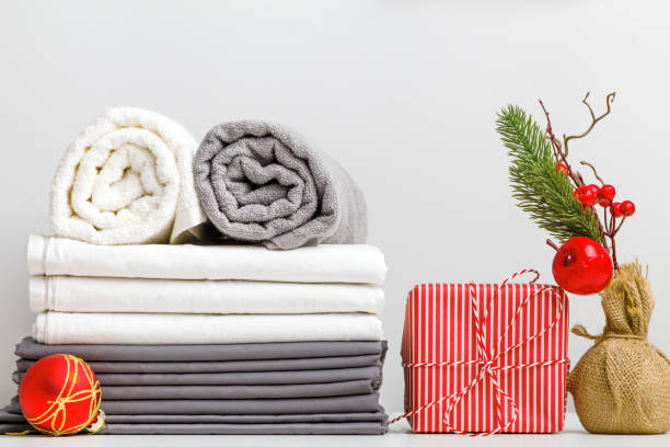 istock Stack of bed linen, bed sheet and folded rolls of towels on a table with Christmas decor 1421072476