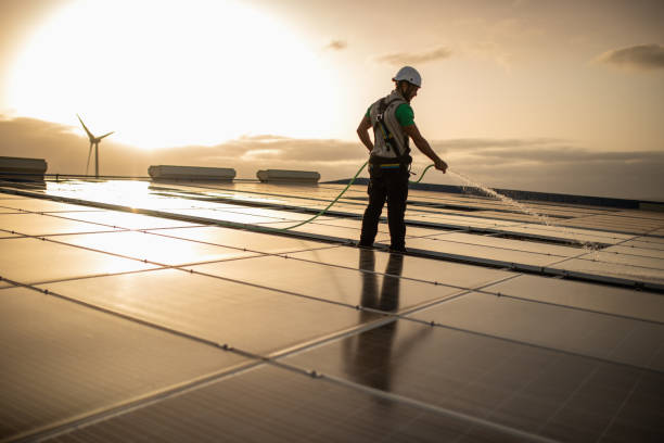 Cleaning equipment at a photovoltaic farm Worker at a solar power plant doing maintenance of the solar panels with a wind turbine in the background. Cleaning panels to maximize production. All my images have been processed in 16 Bits and transfer down to 8 before uploading. industrial cleaning stock pictures, royalty-free photos & images