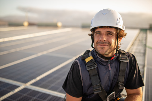 Portrait of a worker, working on solar panels or solar cells on the roof of a factory