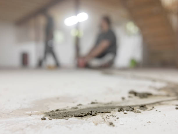 istock Hydrophobic cement for sealing cracks in the basement floor. Focus on fresh cement, with workers walking defocused background. 1421081645