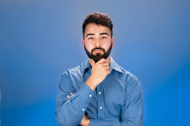 istock Young man touching his chin and looking att camera 1421081815